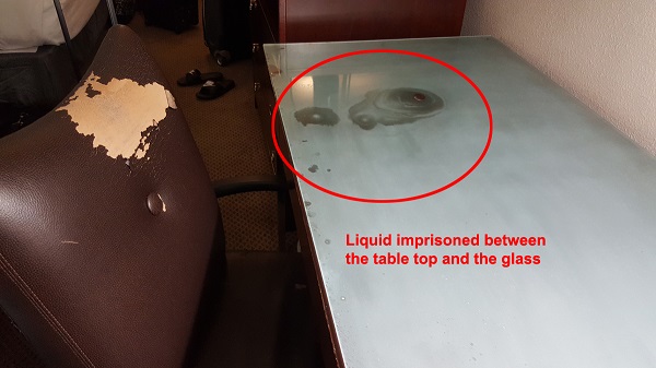 Dirty liquid on table top in a dirty hotel room